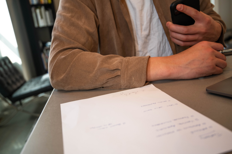 Person am Schreibtisch mit einem unterschriebenen Vertrag und Smartphone